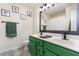 Bright bathroom featuring a double sink vanity with green cabinets and framed botanical art at 5504 Crabtree Park Ct, Raleigh, NC 27612