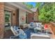 Cozy outdoor living area featuring ample seating, a brick exterior, and wooded view at 5524 Jomali Dr, Durham, NC 27705