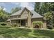 Spacious backyard with a brick home, covered porch, patio seating, a wooden arbor, and manicured green grass at 5901 Charleycote Dr, Raleigh, NC 27614
