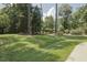 View of a large backyard with a treeline and a wooden arbor with green vines providing ample privacy at 5901 Charleycote Dr, Raleigh, NC 27614