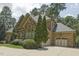 Side view of a brick home featuring a three-car garage, mature landscaping, and a well-maintained lawn at 5901 Charleycote Dr, Raleigh, NC 27614