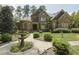 Stunning stone home featuring lush landscaping, a charming fountain, and a curved walkway leading to the entrance at 5901 Charleycote Dr, Raleigh, NC 27614