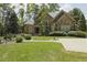 Stunning stone home featuring lush landscaping, mature trees, and a walkway leading to the entrance at 5901 Charleycote Dr, Raleigh, NC 27614