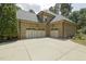 Three-car garage with large concrete driveway, brick exterior, and mature landscaping at 5901 Charleycote Dr, Raleigh, NC 27614