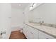Bright bathroom featuring double sinks with granite countertop and white cabinets and wood-look flooring at 604 Natchez Trace, Fuquay Varina, NC 27526