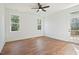 Bright bedroom with wood-look flooring, a ceiling fan, two windows, and a glass paneled door to the deck at 604 Natchez Trace, Fuquay Varina, NC 27526