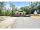 Quaint one-story home with a covered porch and gravel driveway, surrounded by a lush, wooded landscape at 604 Natchez Trace, Fuquay Varina, NC 27526