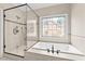 A soaking tub under a decorative window adjacent to the stand-up shower at 608 Driftwood Dr, Gibsonville, NC 27249
