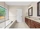 Bathroom featuring double vanity with granite countertops, tiled tub and decorative window at 608 Driftwood Dr, Gibsonville, NC 27249