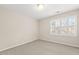 A carpeted bedroom is brightly lit by a modern ceiling fixture and a window with plantation shutters at 608 Driftwood Dr, Gibsonville, NC 27249