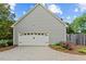Spacious two car garage with a classic white door, beautiful landscaping, and a concrete driveway at 608 Driftwood Dr, Gibsonville, NC 27249