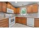 Well-lit kitchen featuring granite countertops, wood cabinets, and modern white appliances at 612 Lakeview Ave, Wake Forest, NC 27587