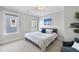 Neutral bedroom with a ceiling fan, two windows, and a queen bed dressed in a white and grey comforter at 707 Sasser St, Raleigh, NC 27604