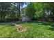 View of a lush backyard featuring a charming storage shed, mature trees, and landscaped retaining wall, perfect for outdoor enjoyment at 713 E Whitaker Mill Rd, Raleigh, NC 27608