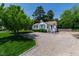Inviting single-story home with a gravel driveway and landscaped front yard surrounded by mature trees under a clear sky at 713 E Whitaker Mill Rd, Raleigh, NC 27608