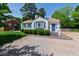 Charming single-story home featuring blue shutters, fresh landscaping, and gravel driveway on a sunny day at 713 E Whitaker Mill Rd, Raleigh, NC 27608