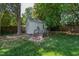 Backyard shot of a storage shed with wooden steps and a rock bed, situated in a lush green yard at 713 E Whitaker Mill Rd, Raleigh, NC 27608