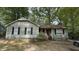 Charming single-story home featuring light green siding, brick foundation, and classic black shutters, framed by mature trees at 7312 Ray Rd, Raleigh, NC 27613