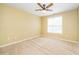 Bedroom with tan walls, carpet, ceiling fan, and large window that provides natural light at 8231 Allyns Landing Way # 302, Raleigh, NC 27615
