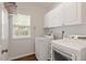 Functional laundry room with washer, dryer, white cabinets and a window for natural light at 8814 Waynick Dr, Raleigh, NC 27617