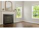 Living room with a fireplace, hardwood floors, and large windows offering views of lush greenery at 8814 Waynick Dr, Raleigh, NC 27617