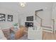 Bright living room featuring a staircase, comfortable seating, a wooden coffee table, and a large television at 908 Kensley Grove Ln # 69, Fuquay Varina, NC 27526