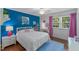 Bright bedroom with hardwood floors, a white bed frame, cheerful blue accent wall and vibrant pink accents at 1008 Winona Rd, Raleigh, NC 27609