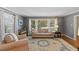 Comfortable living room with large windows, plush sofa, armchair, and stylish area rug on hardwood floors at 1008 Winona Rd, Raleigh, NC 27609