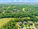 Aerial view featuring beautiful homes surrounded by lush greenery, a golf course, and a serene lake in the background at 1046 Covered Bridge Trl, Chapel Hill, NC 27517
