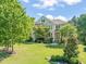 Landscaped front yard showcases a lovely brick home with shutters, complemented by lush greenery and mature trees at 1046 Covered Bridge Trl, Chapel Hill, NC 27517