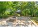 Outdoor fire pit area with stone patio and play structure surrounded by mature trees at 1046 Covered Bridge Trl, Chapel Hill, NC 27517