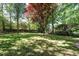 Expansive backyard features a variety of trees, including a vibrant red tree that offers lots of shade at 105 Kenmont Dr, Holly Springs, NC 27540