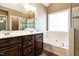 Bright bathroom featuring double vanity, soaking tub, and tiled shower with glass enclosure at 105 Kenmont Dr, Holly Springs, NC 27540