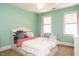 Charming bedroom with two windows, a ceiling fan, and a cozy bed with a patterned comforter at 105 Kenmont Dr, Holly Springs, NC 27540