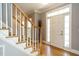 Bright foyer with hardwood floors, staircase with white banisters, and a front door with sidelights at 105 Kenmont Dr, Holly Springs, NC 27540