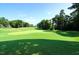 Beautiful green golf course surrounded by mature trees under a clear, sunny sky at 105 Kenmont Dr, Holly Springs, NC 27540