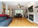Cozy living room with hardwood floors, a ceiling fan and a fireplace with a mounted television at 105 Kenmont Dr, Holly Springs, NC 27540