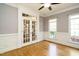 Bright room featuring hardwood floors, French doors, wainscoting, neutral walls and two large windows at 105 Kenmont Dr, Holly Springs, NC 27540