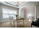 Well-lit dining room featuring a chandelier, large window, and a table with four white chairs at 11 Piccadilly Ct, Durham, NC 27713