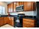 A kitchen showcasing wood cabinets, stainless steel microwave, black countertops, and a black oven at 11 Piccadilly Ct, Durham, NC 27713