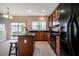An open-concept kitchen offers an island, wood cabinets, black appliances, and backyard views from the window at 11 Piccadilly Ct, Durham, NC 27713