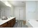 Bright bathroom featuring double sinks, a soaking tub, and stylish gray wood-look flooring at 1106 Red Crest Ln, Durham, NC 27704