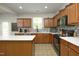 Well-lit kitchen featuring wooden cabinetry, stainless steel appliances, an island, and a tiled backsplash at 1106 Red Crest Ln, Durham, NC 27704
