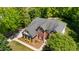 Aerial view of a two-story brick home with lush landscaping and a well-maintained roof at 1258 Jamestowne Dr, Elon, NC 27244