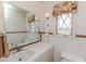 Bathroom featuring a tile countertop, a large mirror, and a window at 1706 Carthage St, Sanford, NC 27330