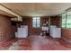 Bright laundry room with a washer, dryer, sink, and ample space, featuring exposed brick walls and a window view at 1706 Carthage St, Sanford, NC 27330