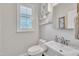 Clean half bathroom with pedestal sink, framed mirror and white accents with wainscotting and window at 201 Bog Hill Ln, Cary, NC 27519