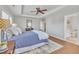 Inviting main bedroom featuring a tray ceiling, ceiling fan, wood floors, and a glimpse into the ensuite bathroom at 201 Bog Hill Ln, Cary, NC 27519