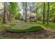 A backyard putting green surrounded by mature trees, adds a touch of leisure at 208 W Camden Forest Dr, Cary, NC 27518