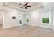 Spacious main bedroom featuring tray ceilings, a ceiling fan, and windows with natural light at 208 W Camden Forest Dr, Cary, NC 27518